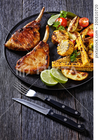 bbq tomahawk pork chop with corn and potatoes bbq tomahawk pork chop with corn and potatoes 100810720
