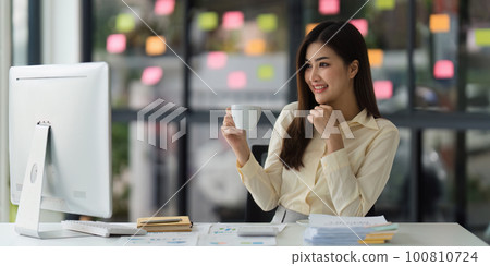 Beautiful Asian Banker or Accountant makes financial report and tax, analyzes profits. Accountant checks status of financial 100810724