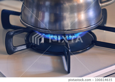 A kettle on a lit gas stove 100814635