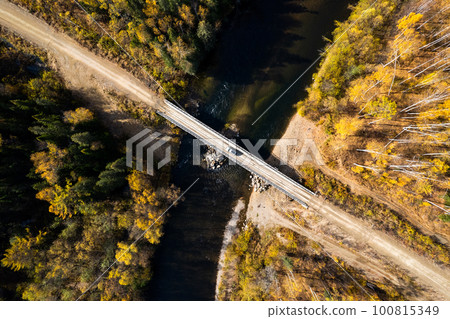 SUV on wooden bridge over small mountain river. Autumn forest. 100815349