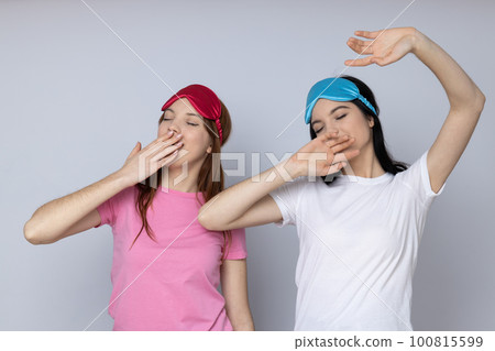 Two beautiful young women, sisters - twins on light gray background 100815599
