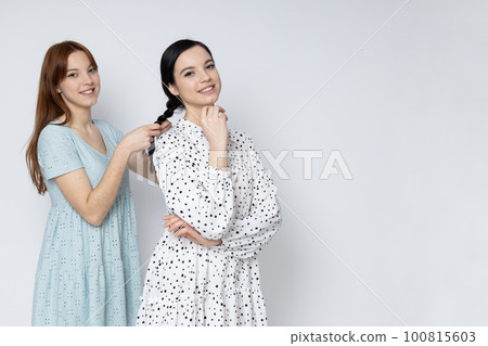 Two beautiful young women, sisters - twins on white background 100815603
