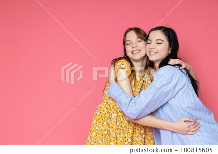Two beautiful young women, sisters - twins on pink background Two beautiful young women, sisters - twins on pink background 100815605