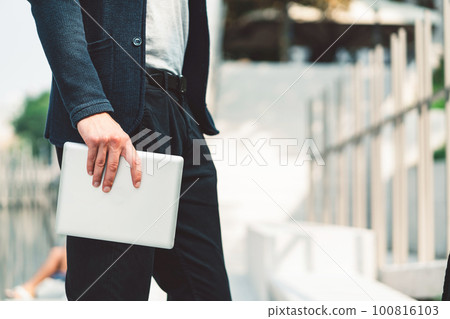 Waist down unrecognizable man side view holding a digital tablet in his hand outside 100816103