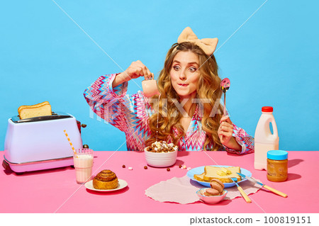 Food pop art photography. Redhead girl with bow preparing milk flakes with hungry eyes on pink tablecloth over light blue background Food pop art photography. Redhead girl with bow preparing milk flakes with hungry eyes on pink tablecloth over light blue background 100819151