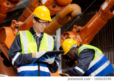 Two young engineer man checking and maintenance machine robot arms. Two young engineer man checking and maintenance machine robot arms. 100820346