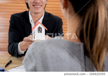 Young realtor man real estate giving house model to hands customer while agreement. Young realtor man real estate giving house model to hands customer while agreement. 100820395
