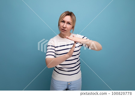 concentrated blond girl shows hand gesture letter t on blue background with copy space concentrated blond girl shows hand gesture letter t on blue background with copy space 100820778