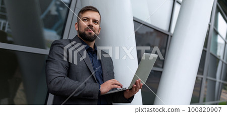 pensive male architect with a laptop works on the background of the building pensive male architect with a laptop works on the background of the building 100820907
