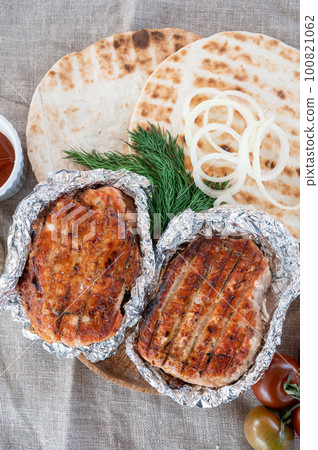 Grilled pork meat in foil with flapjack and vegetables 100821062