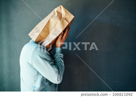 Upset man with a paper bag on head covering eyes with both hands. Profile view, copy space Upset man with a paper bag on head covering eyes with both hands. Profile view, copy space 100821092