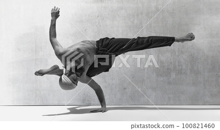 Black and white image, monochrome. Standing at one hand. Bearded strong man training shirtless, practising yoga exercises 100821460
