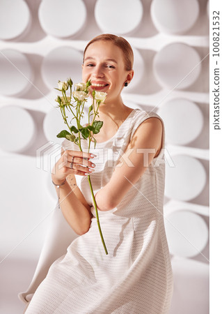 A young woman with special needs with flowers in her hand, a girl born without a hand, in white dress on a white background in the rays of the sun beauty fashion concept A young woman with special needs with flowers in her hand, a girl born without a hand, in white dress on a white background in the rays of the sun beauty fashion concept 100821532