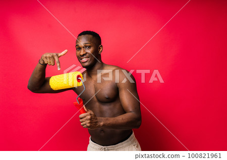 African painter focused on work holding professional roller to paint an interior wall, studio. African painter focused on work holding professional roller to paint an interior wall, studio. 100821961
