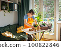 Woman potting indoor spring flowers and plants 100822846