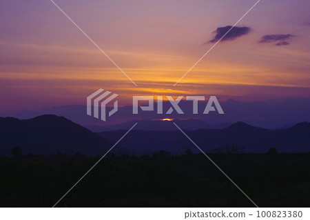 Sun hiding behind the mountains. Sunset background. 100823380
