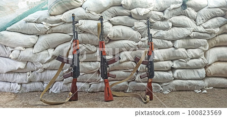 Three Kalashnikovs standing near sandbagged fortifications. AK-74 outdoor 100823569