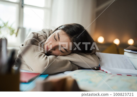 Teenage girl fall asleep during studying in her room. 100823721