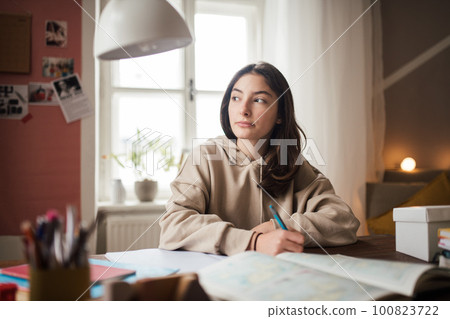 Young teenage girl studying in her room. 100823722