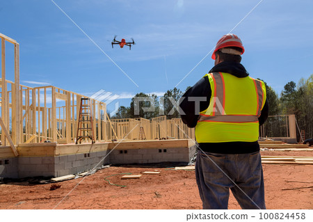 An inspector checks quality of construction works on construction site with help drone An inspector checks quality of construction works on construction site with help drone 100824458