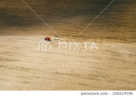 Aerial View. Tractor With Seed Drill Machine Sowing The Seeds For Crops In Spring Season. Beginning Of Agricultural Spring Season. Countryside Field Landscape. Natural Rural Background Aerial View. Tractor With Seed Drill Machine Sowing The Seeds For Crops In Spring Season. Beginning Of Agricultural Spring Season. Countryside Field Landscape. Natural Rural Background 100824590