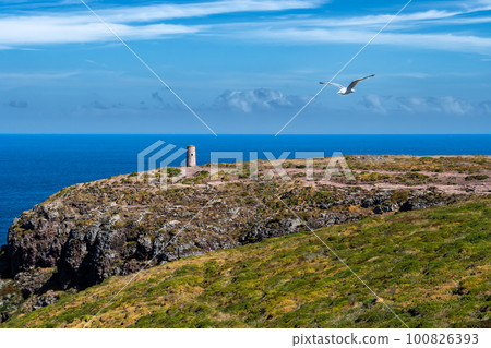 Cliffs At Atlantic Coast With Ancient Lighthouse At Cap Frehel In Brittany, France; Phare du Cap Frehel Cliffs At Atlantic Coast With Ancient Lighthouse At Cap Frehel In Brittany, France; Phare du Cap Frehel 100826393