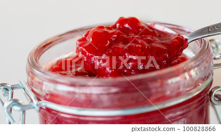 Preparation and preservation of strawberry jam in a glass jar, close up 100828866