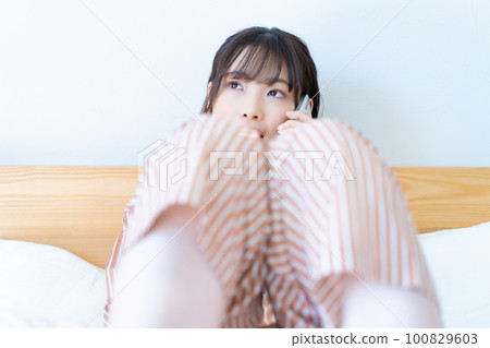 穿著睡衣的年輕女人用智能手機打電話 100829603
