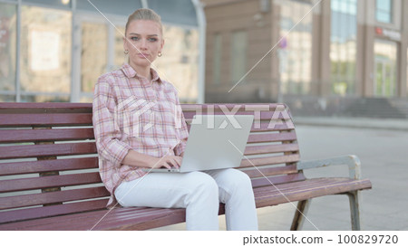 Rejecting Young Woman in Denial While using Laptop Sitting Outdoor on Bench 100829720