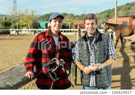 Married couple owners of stable against the backdrop of corral for walking horses 100829957