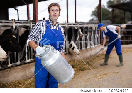 Farmer man holds milk can at cow farm 100829965