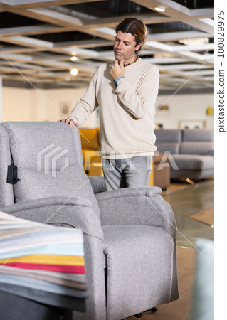 Man choosing armchair in furniture store Man choosing armchair in furniture store 100829975