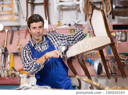 Portrait of middle-aged skillful repairman carpenter renovating chair furniture using tools in woodwork studio 100830165