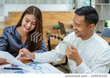 startup business, portrait of two entrepreneurs using computers and financial budget documents to make marketing plans to increase profits. 100830203