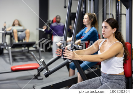 Caucasian woman using chest fly machine for training in gym 100830264