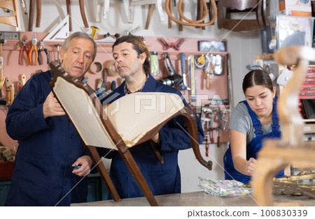 Two male restorers inspecting vintage chair before starting restoration in workshop Two male restorers inspecting vintage chair before starting restoration in workshop 100830339
