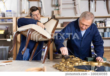employees restore antique chair with twisted legs and mirror in massive carved wooden frame employees restore antique chair with twisted legs and mirror in massive carved wooden frame 100830393
