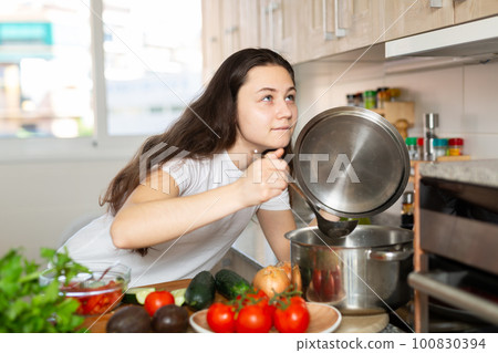 Woman holding cooking ladle spoon while cooking soup 100830394