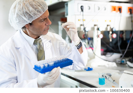 Portrait of an adult male using equipment to work in a laboratory 100830400