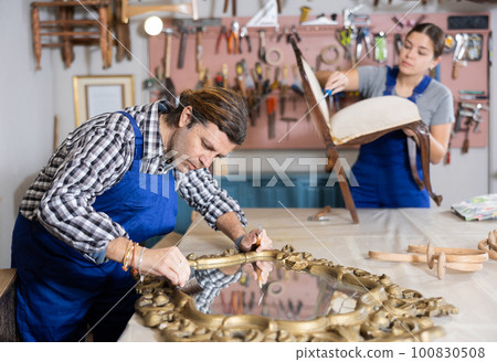 Portrait of middle-aged skillful repairman carpenter renovating mirror frame using tools in woodwork studio Portrait of middle-aged skillful repairman carpenter renovating mirror frame using tools in woodwork studio 100830508