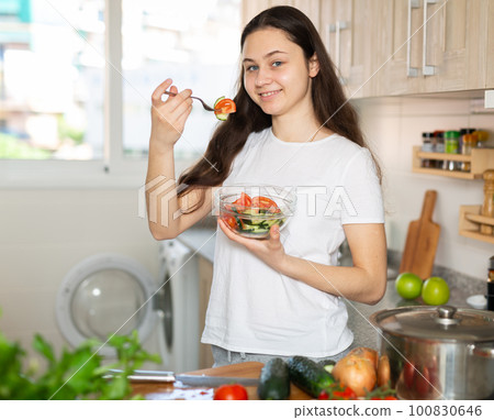 Woman eating vegetable salad at home kitchen Woman eating vegetable salad at home kitchen 100830646