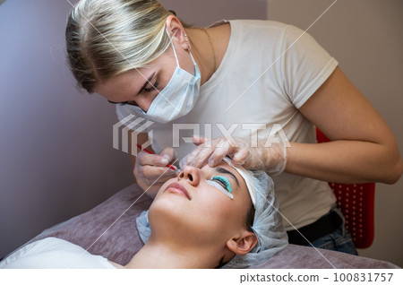 Close-up portrait of a woman on eyelash lamination procedure.  100831757