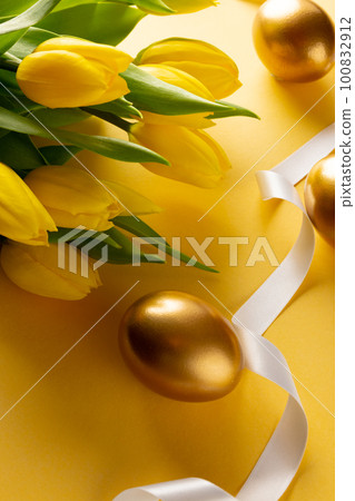 Image of gold easter eggs with yellow tulips and copy space on yellow background 100832912