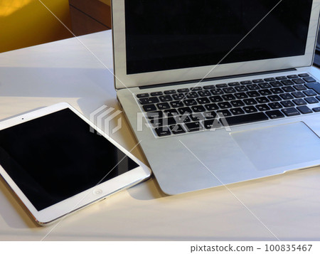 Laptop and tablet by window in cafe 100835467