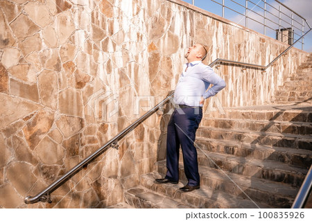 Portrait of a senior professional man in a suit with various problems. A middle-aged businessman with descends the stairs. Portrait of a senior professional man in a suit with various problems. A middle-aged businessman with descends the stairs. 100835926