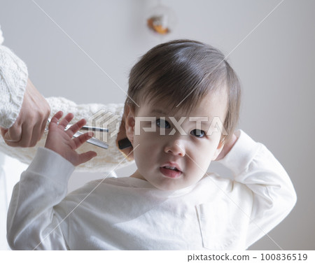 Boy having his hair cut by his mother 100836519