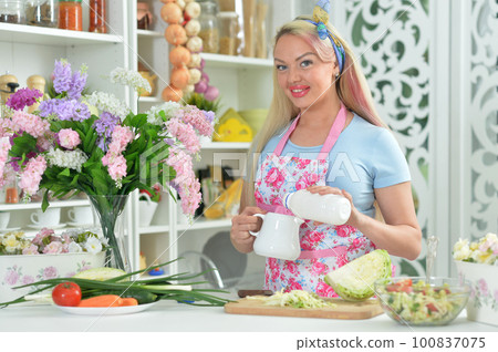 cute young woman cooking salad in kitchen 100837075