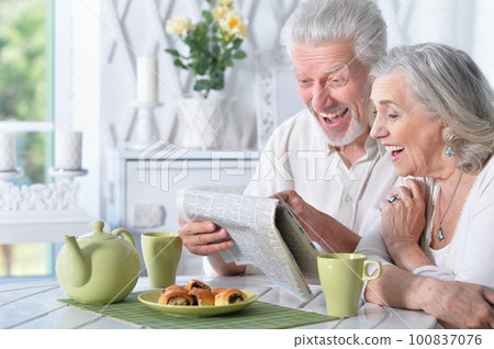 Close-up portrait of a senior couple with newspaper Close-up portrait of a senior couple with newspaper 100837076