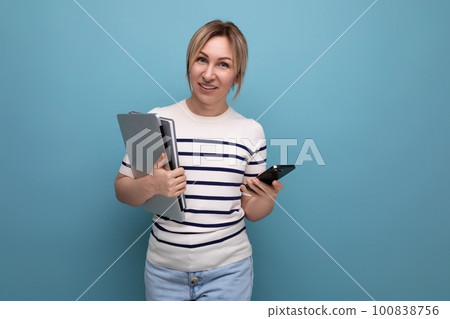 close up photo of smart blond female student in casual outfit with laptop and notepad on blue 100838756