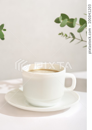 espresso coffee in a white classic cup, vertical, good morning, green leaves around a cup espresso coffee in a white classic cup, vertical, good morning, green leaves around a cup 100841203